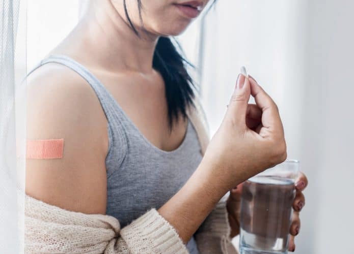 Mulher tomando paracetamol depois da vacina