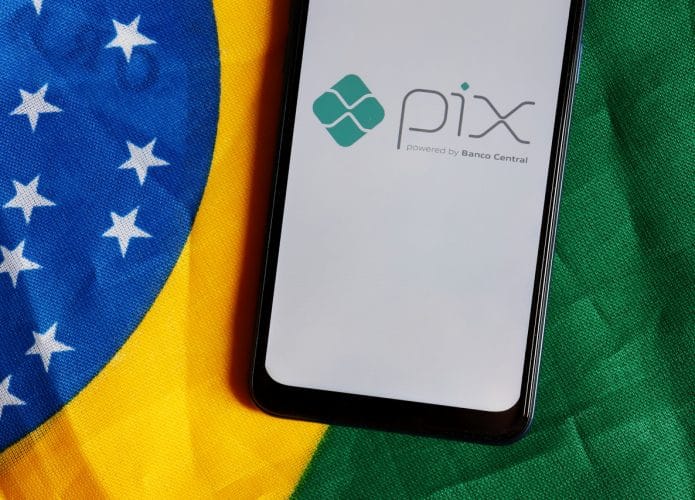 Logo do PIX em smartphone com uma bandeira do Brasil ao fundo