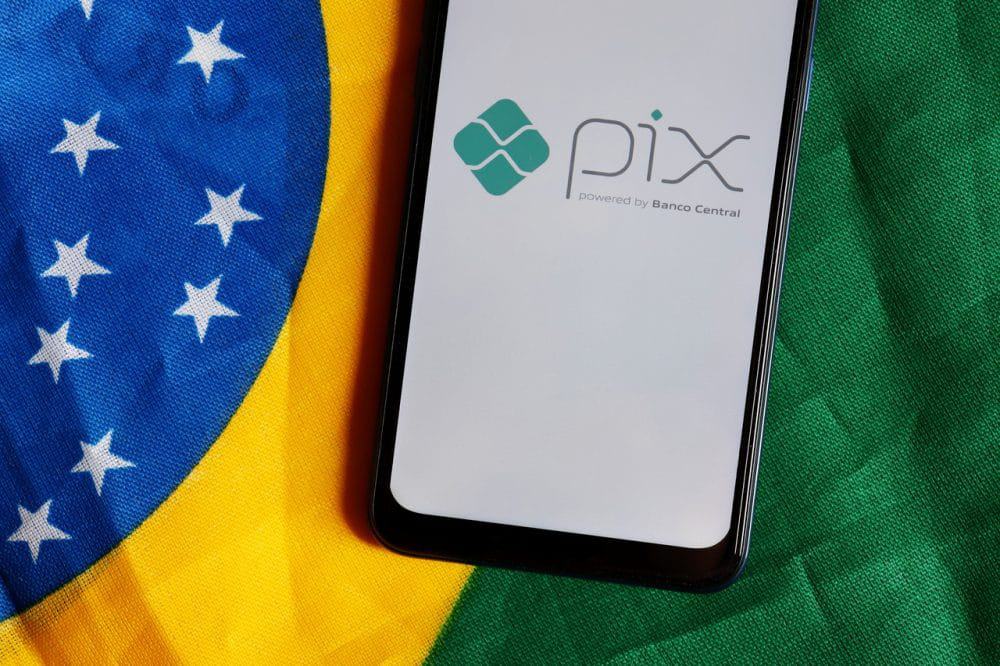 Logo do PIX em smartphone com uma bandeira do Brasil ao fundo