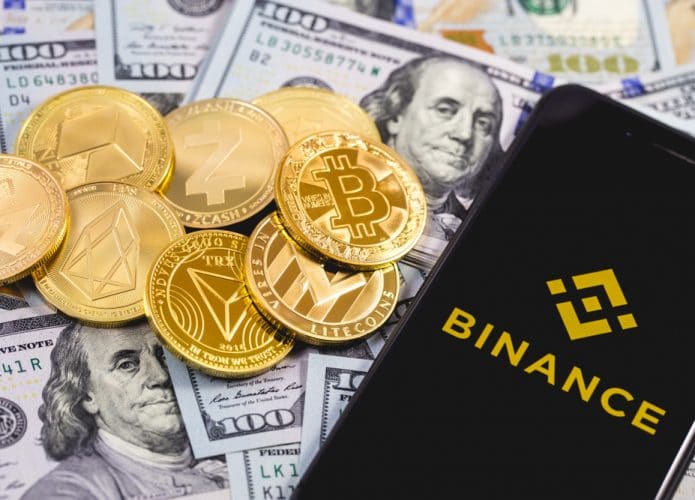 Logo da Binance ao lado de criptomoedas e dólares