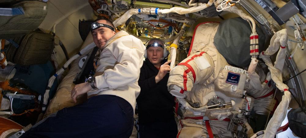 Pyotr Dubrov (à esquerda) e Oleg Novitskiy preparam trajes espaciais russos Orlan para uma caminhada espacial