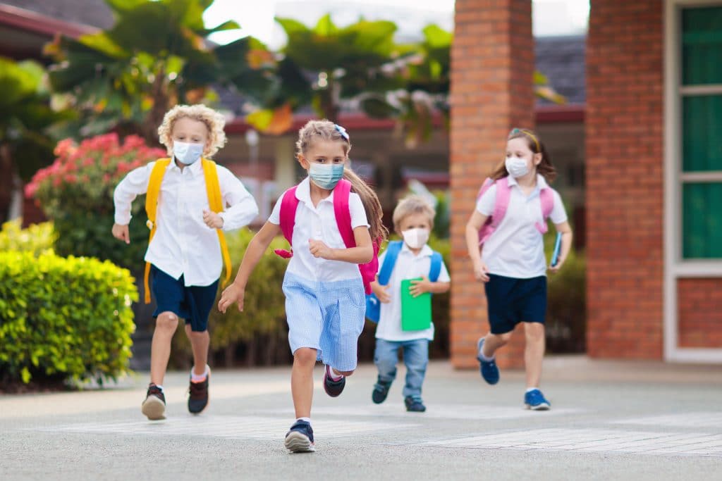 crianças de máscara correndo na escola