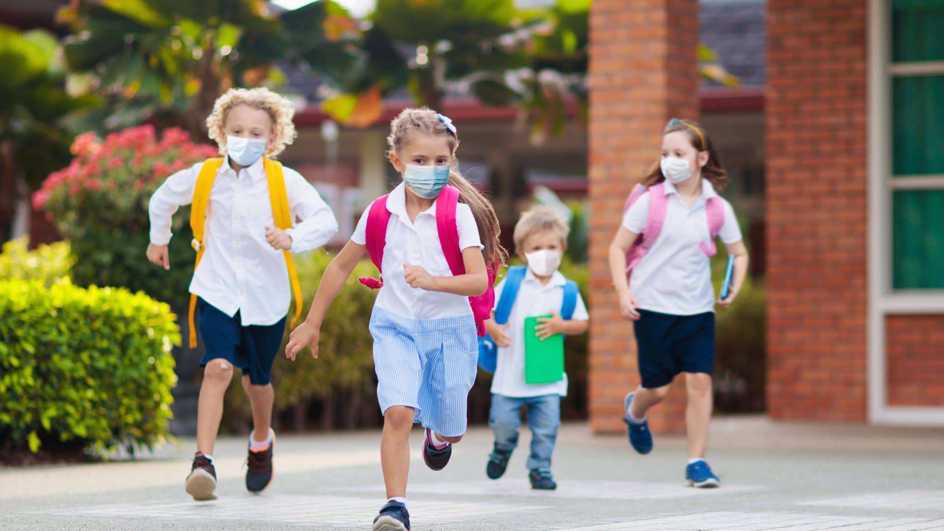 crianças de máscara correndo na escola