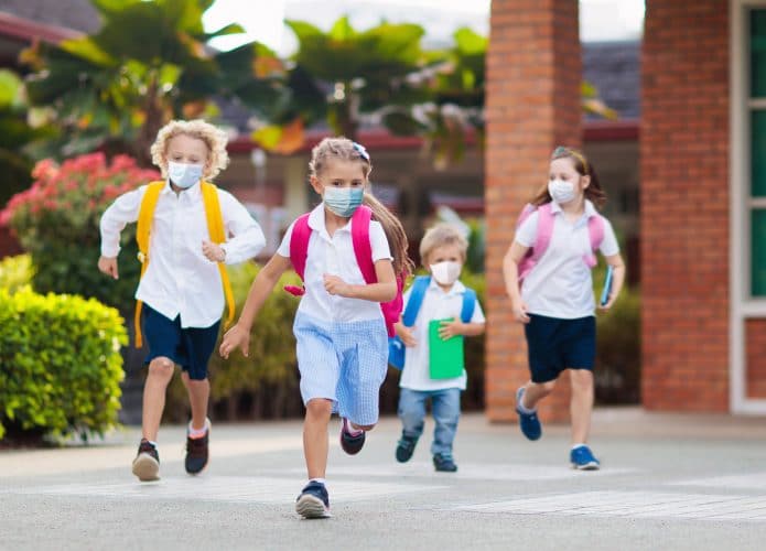 crianças de máscara correndo na escola