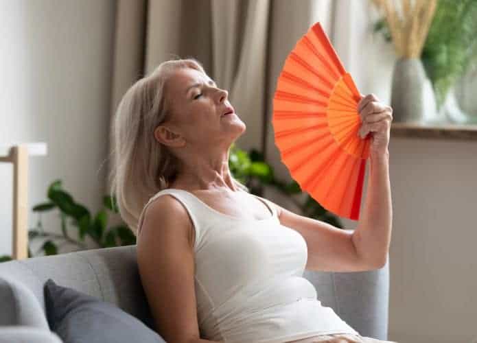 mulher se abanando pelo calor da menopausa