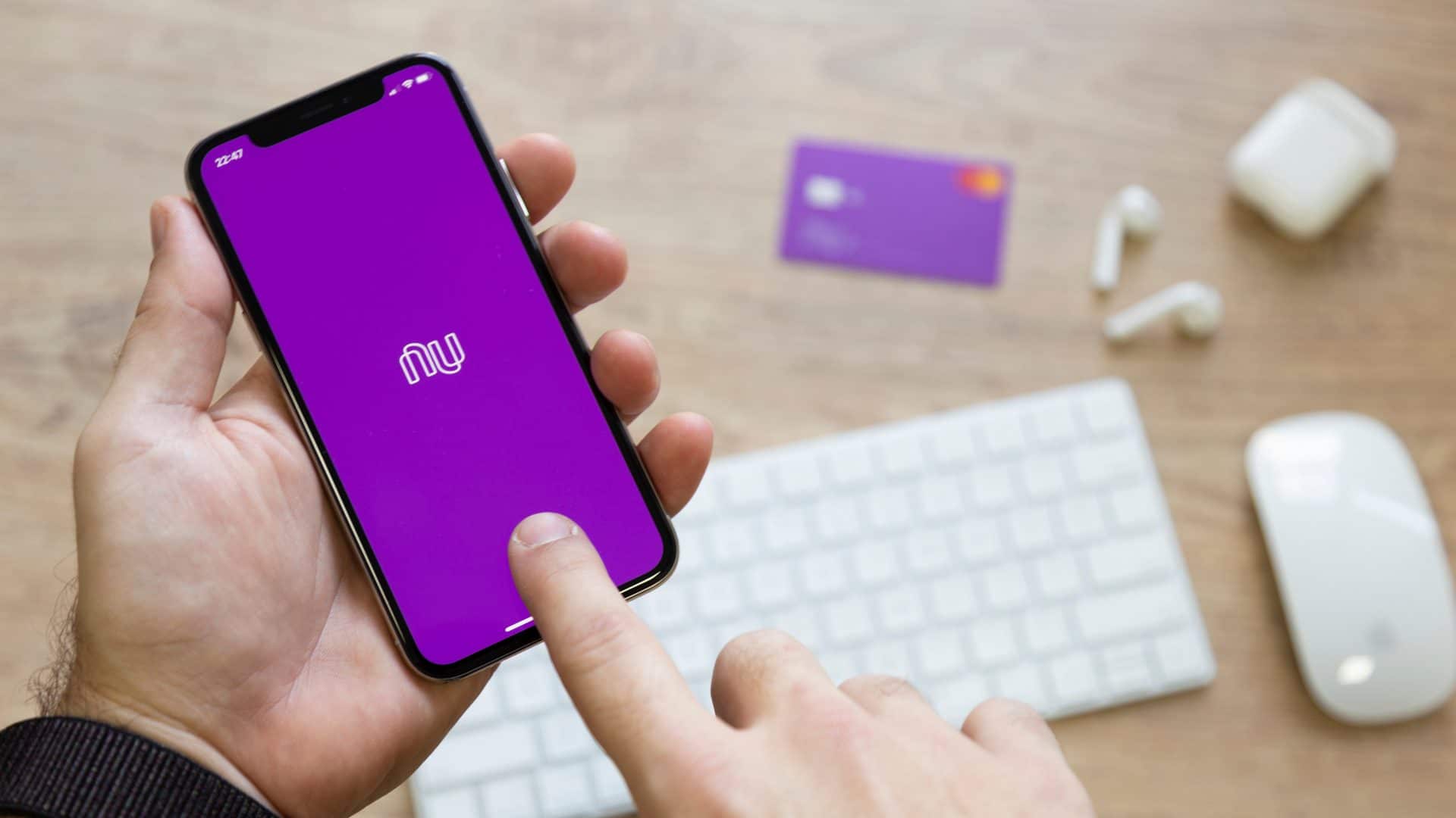 Um par de mãos segura celular com app do Nubank aberto