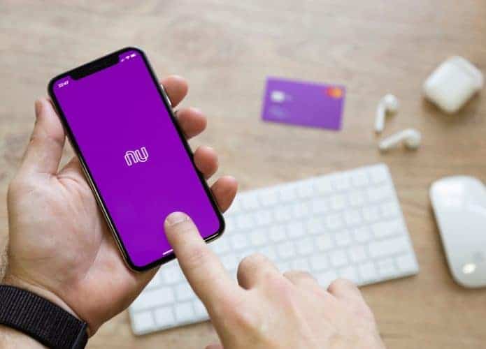 Um par de mãos segura celular com app do Nubank aberto