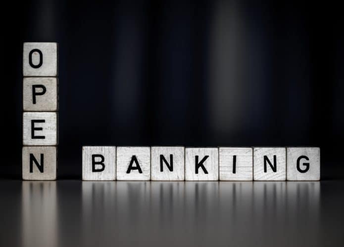 Imagem de fundo preto mostra alguns cubos empilados, cada um com uma letra, formando a palavra open banking