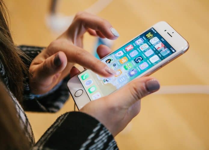 Imagem mostra um par de mãos mexendo em um iPhone