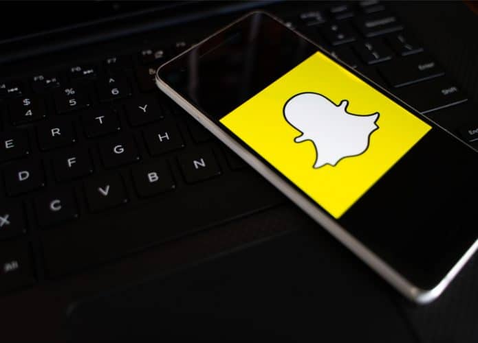 Celular com ícone do Snapchat na tela, colocado sobre teclado de computador