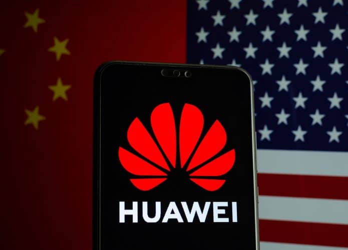 Logo da Huawei exibido em smartphone e ao fundo bandeiras da China e Estados Unidos