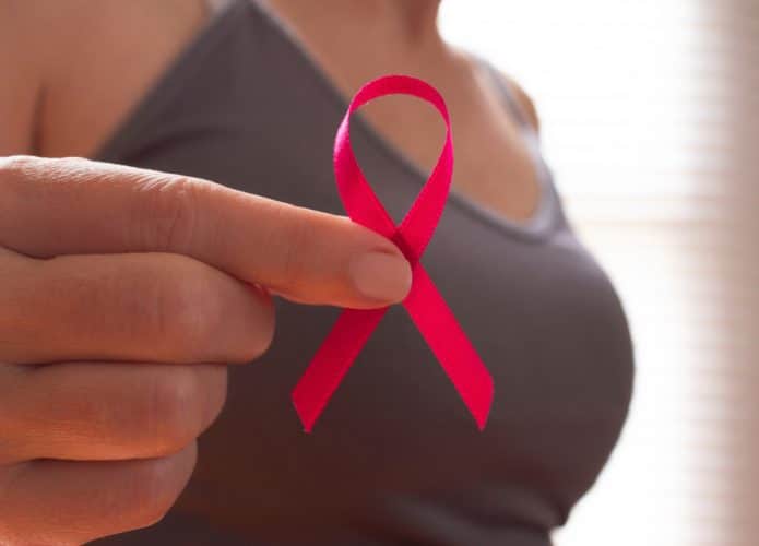 Mulher segurando fita rosa em representação do câncer de mama