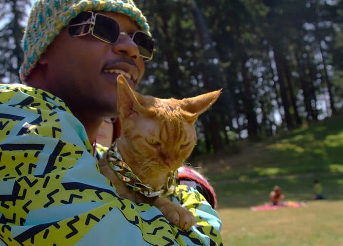 O influencer Moshow e segura um de seus gatos.