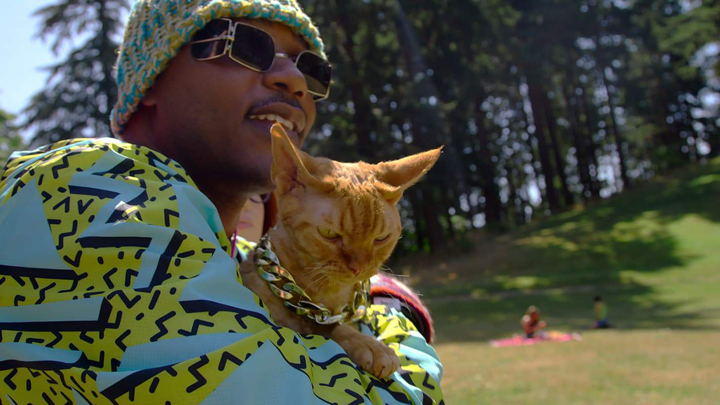 O influencer Moshow e segura um de seus gatos.