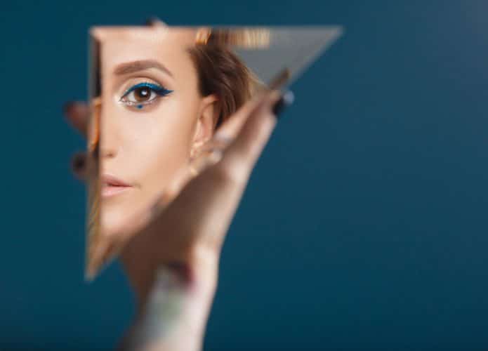 Imagem mostra uma mulher olhando para seu reflexo no espelho