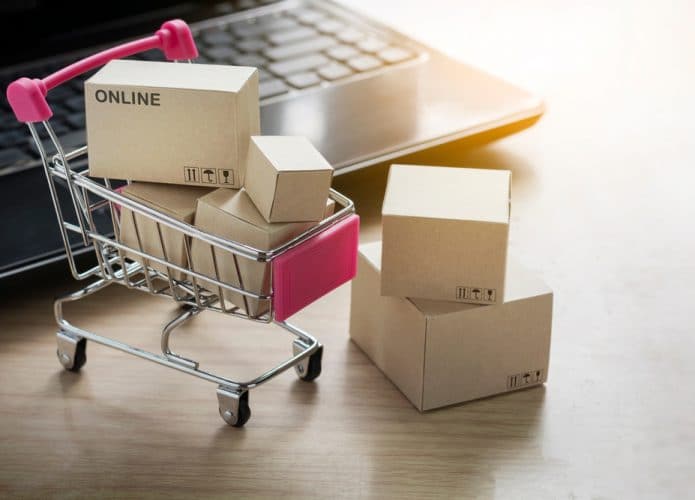 Carrinho de compras cheio de caixas ao lado de um notebook
