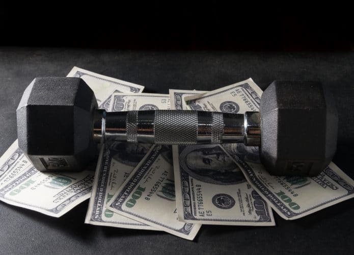 Ilustração de halter de academia em cima de notas de dólar