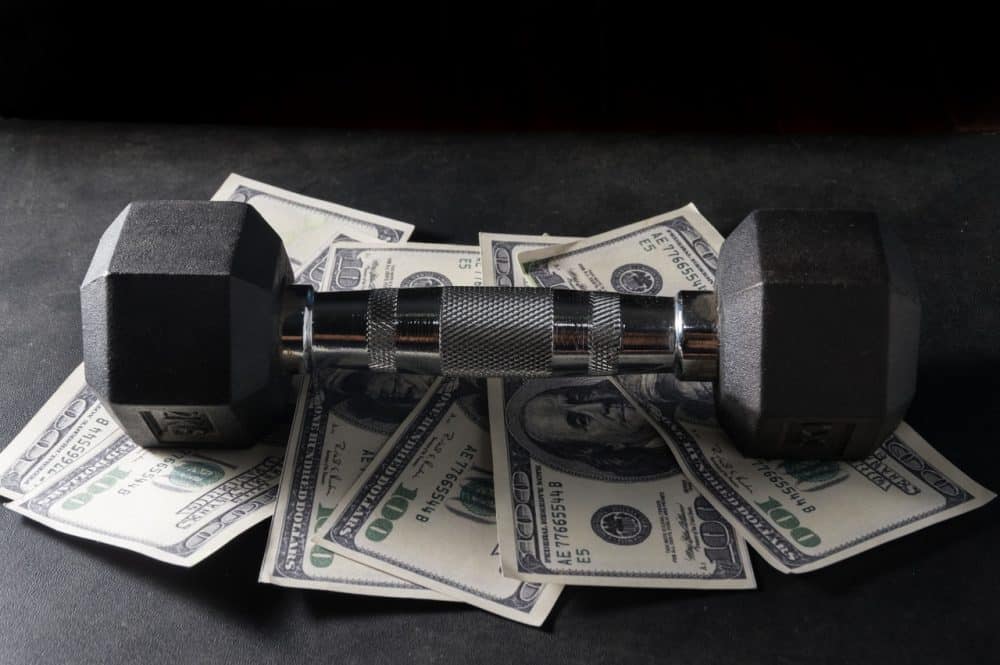 Ilustração de halter de academia em cima de notas de dólar