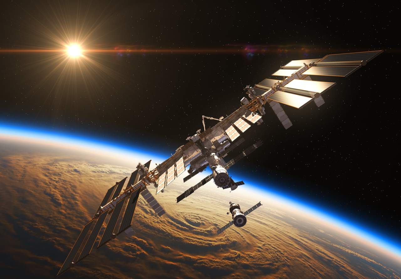 Imagem mostra a Estação Espacial Internacional, com a Terra e o Sol vistos no fundo