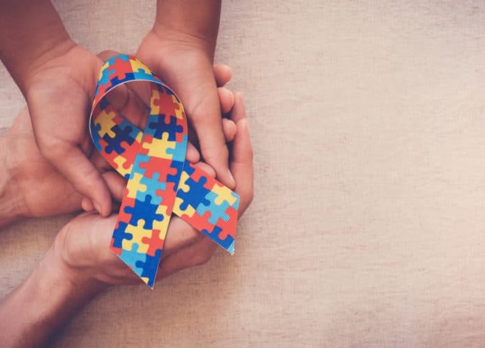 Mãos segurando uma fita estampada com um quebra-cabeça colorido