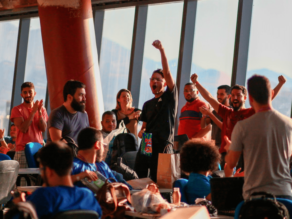 Imagem mostra um grupo de jogens comemorando durante o hackaton Hack Olimpic Games