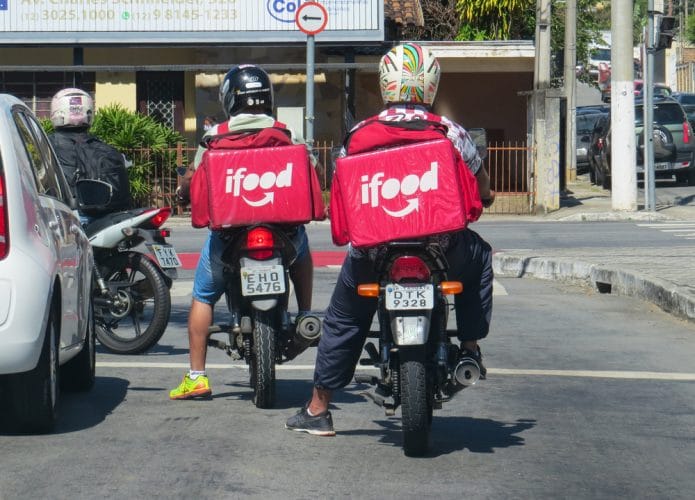 Dois motoboys com mochilas doiFood