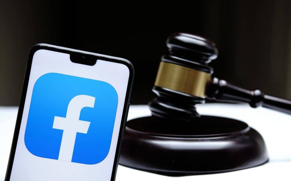 Logo do Facebook exibido em smartphone ao lado de um martelo de tribunal