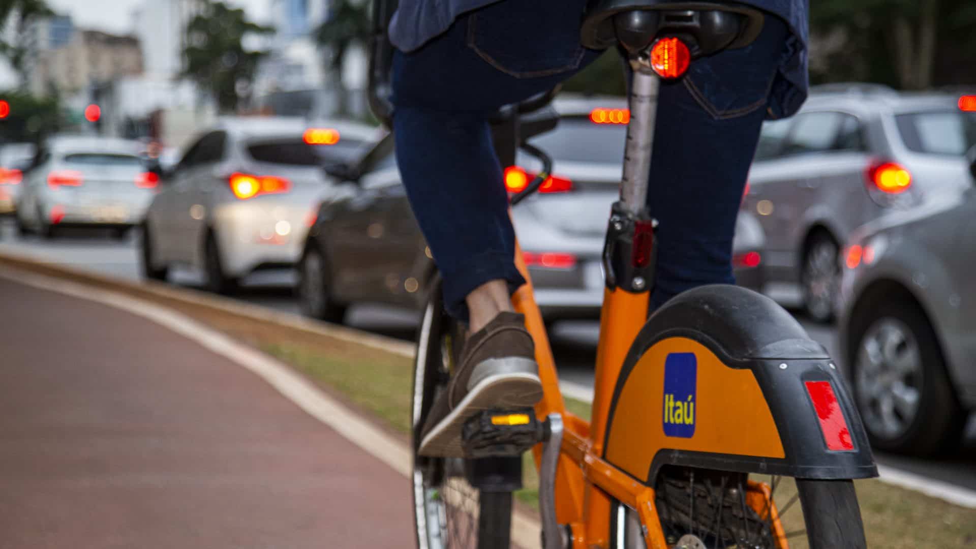 Foto mostra uma bike da Tembici, em parceria com o Itaú, em uma ciclovida da cudade; uma pessoa está pedalando a bicicleta