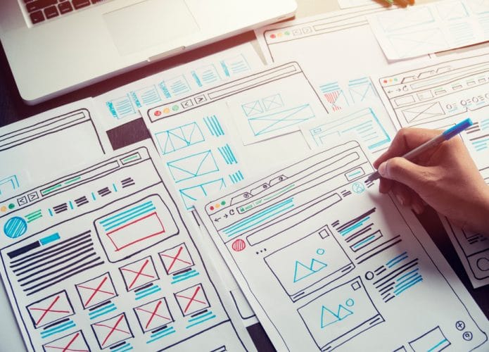Imagem mostra uma mão desenhando templates para aprimorar a user experience de um aplicativo