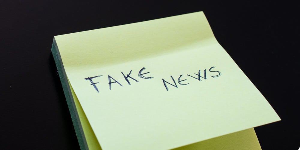 yellow-sticky-note-with-fake-news-written-on-first-paper-picture-id864584344