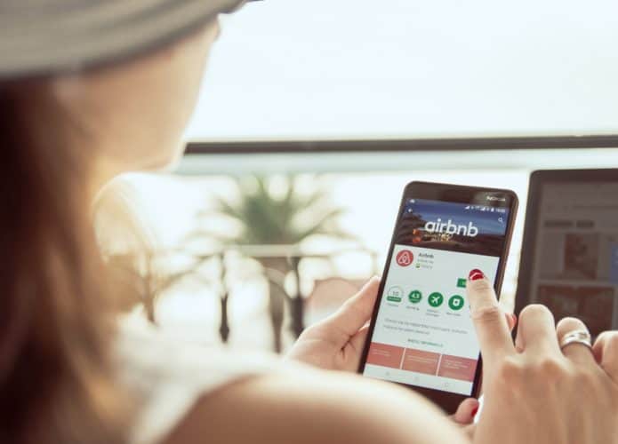 Mulher mexendo no aplicativo do Airbnb