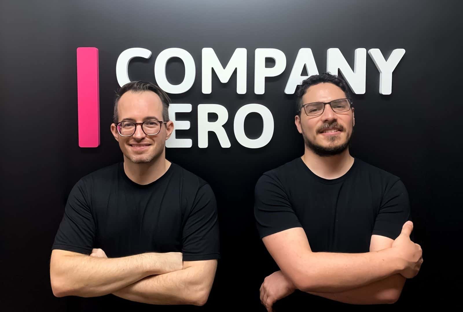 Na imagem, os cofundadores da Company Hero, Miklos Grof e Diego Izquierdo; ao fundo, em uma parede preta, está o logo da empresa em letra caixa