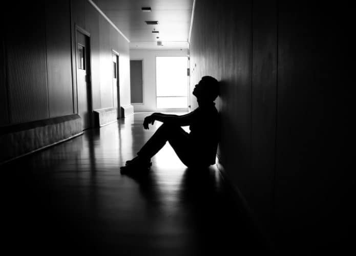 Homem sentado em um corredor escuro