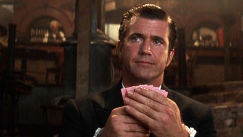 Mel Gibson segura cartas de baralho em cena do filme. 