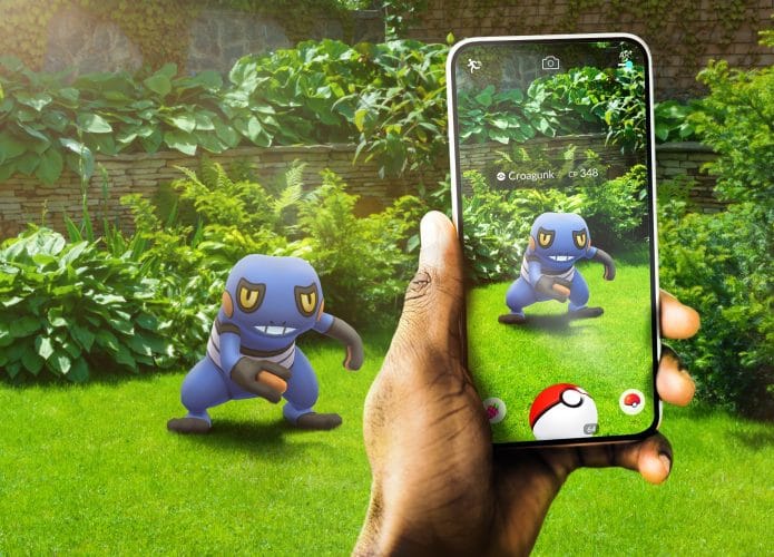 Imagem promocional de Pokémon Go mostra smartphone exibindo imagem do pokémon Croagunk em realidade aumentada.