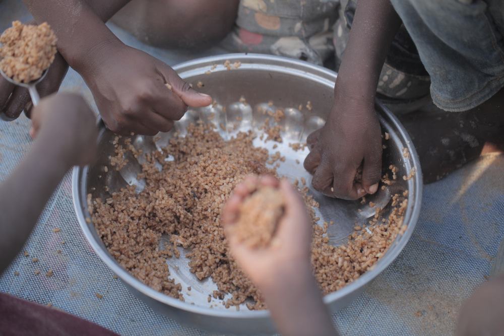 Crianças colocando as mãos em um prato de comida 