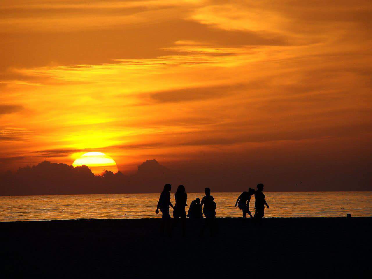 Pessoas caminham na praia