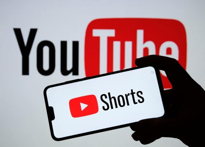 homem segura celular com logo do YouTube Shorts
