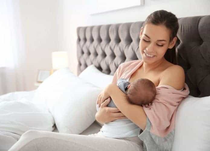mulher amamentando sentada na cama