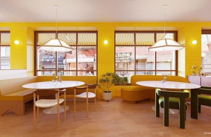 Imagem mostra, ao fundo, janelas abertas em uma parede amarela; à frente mesas com cadeiras dispostas no espaço que é a parte interna do Bumble Brew, restaurante físico do aplicativo de econtros Bumble