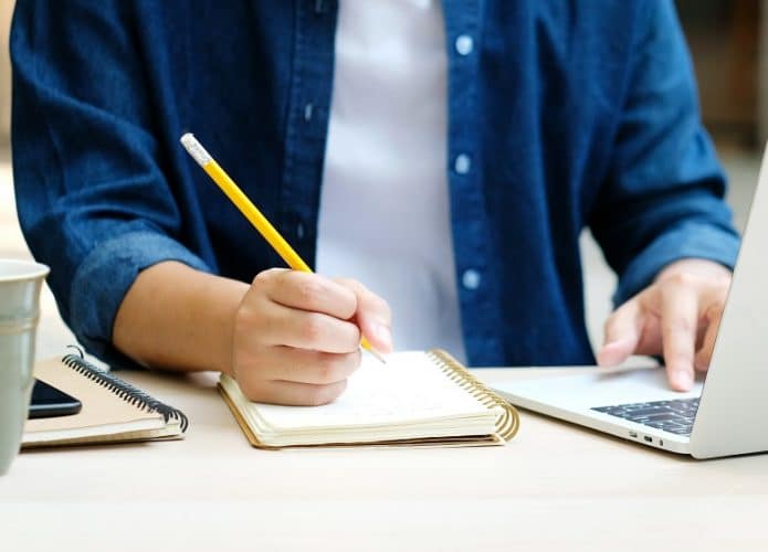 homem estudando escrevendo em caderno e notebook