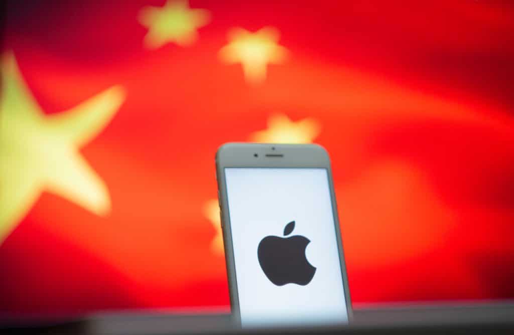 Um smartphone é exibido à frente da bandeira chinesa, com o logotipo da Apple em sua tela