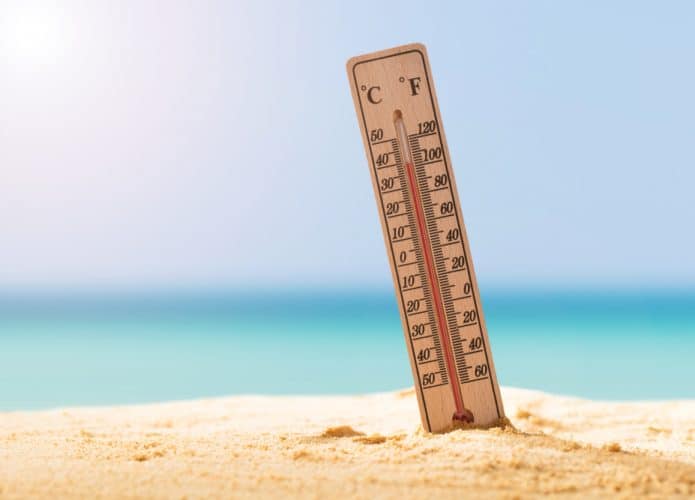 termometro fincado na areia da praia mostrando calor