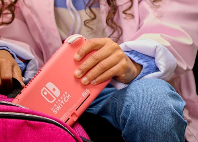 Console Nintendo Switch Lite na cor coral sendo colocado em uma bolsa