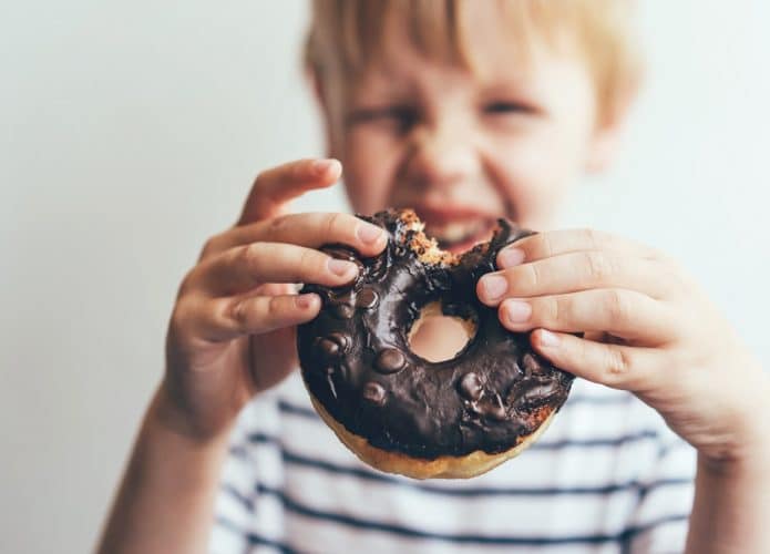 Criança comendo rosquinha de chocolate