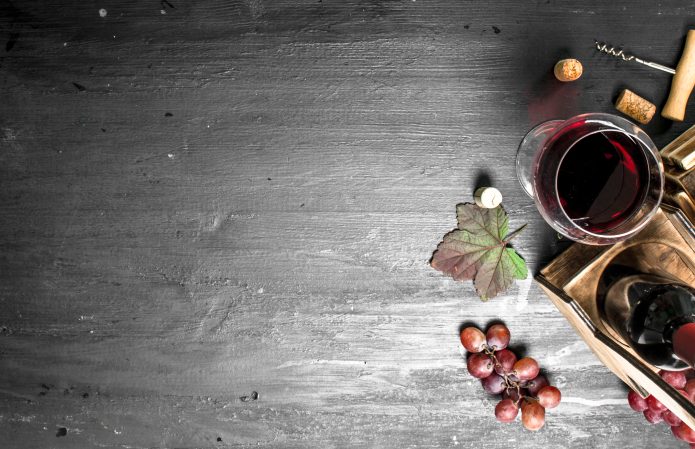 Taça e garrafa de vinho ao lado de uvas