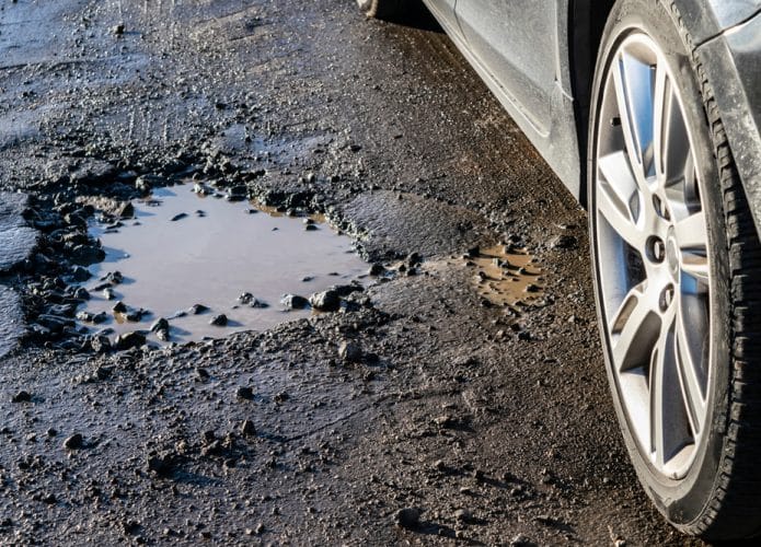 Roda de carro perto de um buraco na estrada