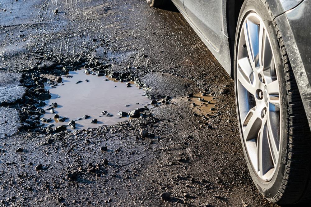 Roda de carro perto de um buraco na estrada