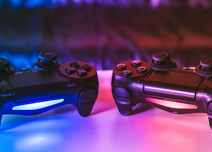 dois controles de PS4 em cima de uma mesa