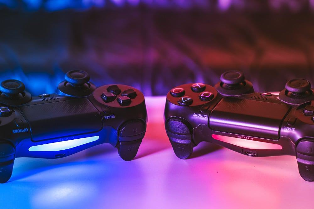 dois controles de PS4 em cima de uma mesa